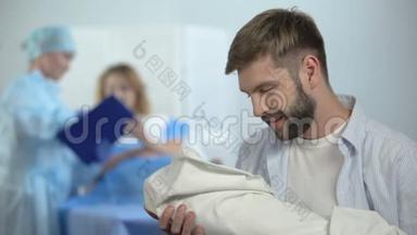 幸福的父亲抱着新生儿在护士解释妻子产后护理